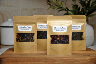 A photo of four loose-leaf tea packs displayed side by side, each with vibrant, eco-friendly packaging. The labels showcase unique tea blends available in the one-time shop, offering a variety of flavors and wellness benefits. 